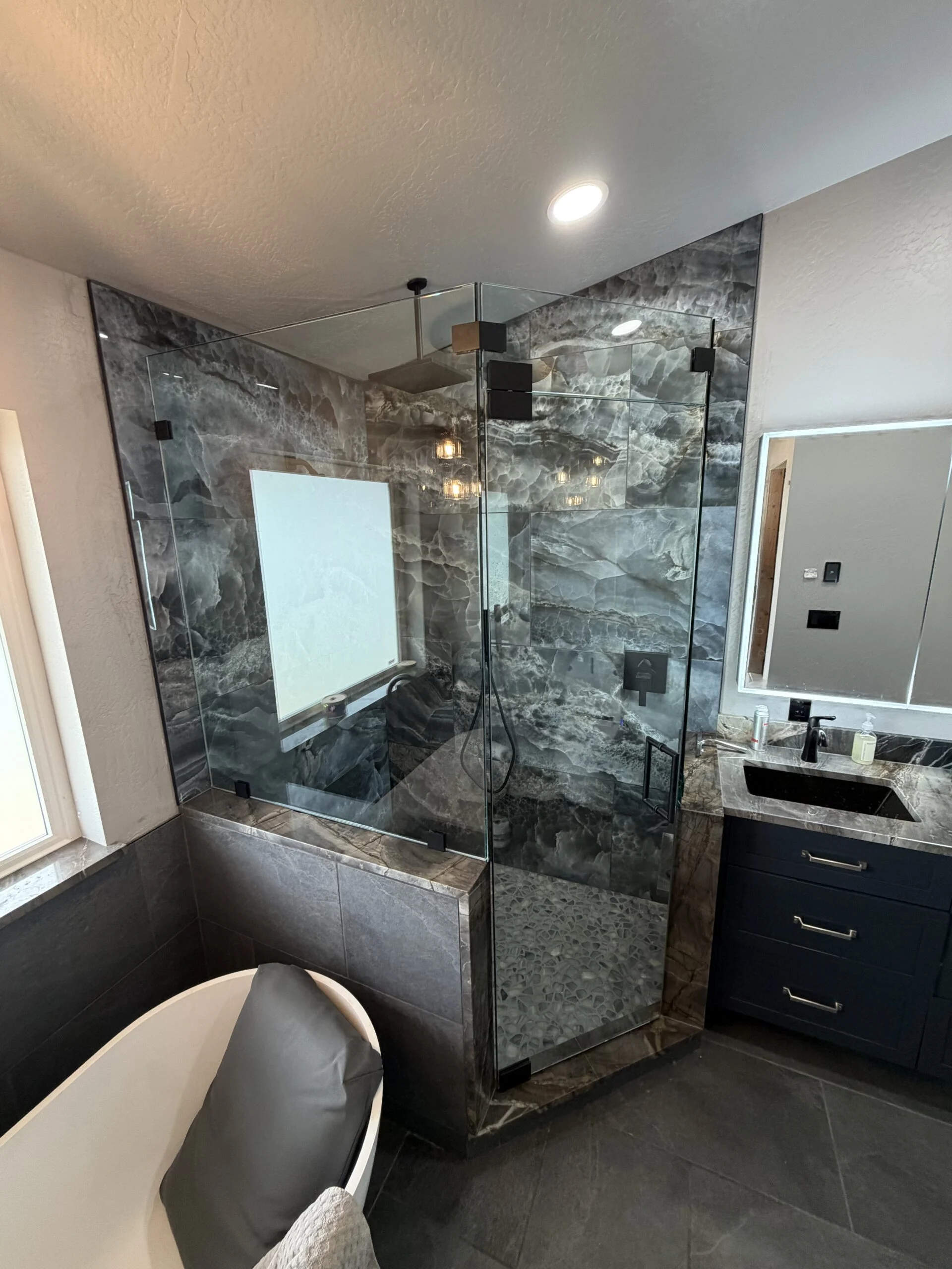 Frameless glass shower enclosure in a modern marble bathroom