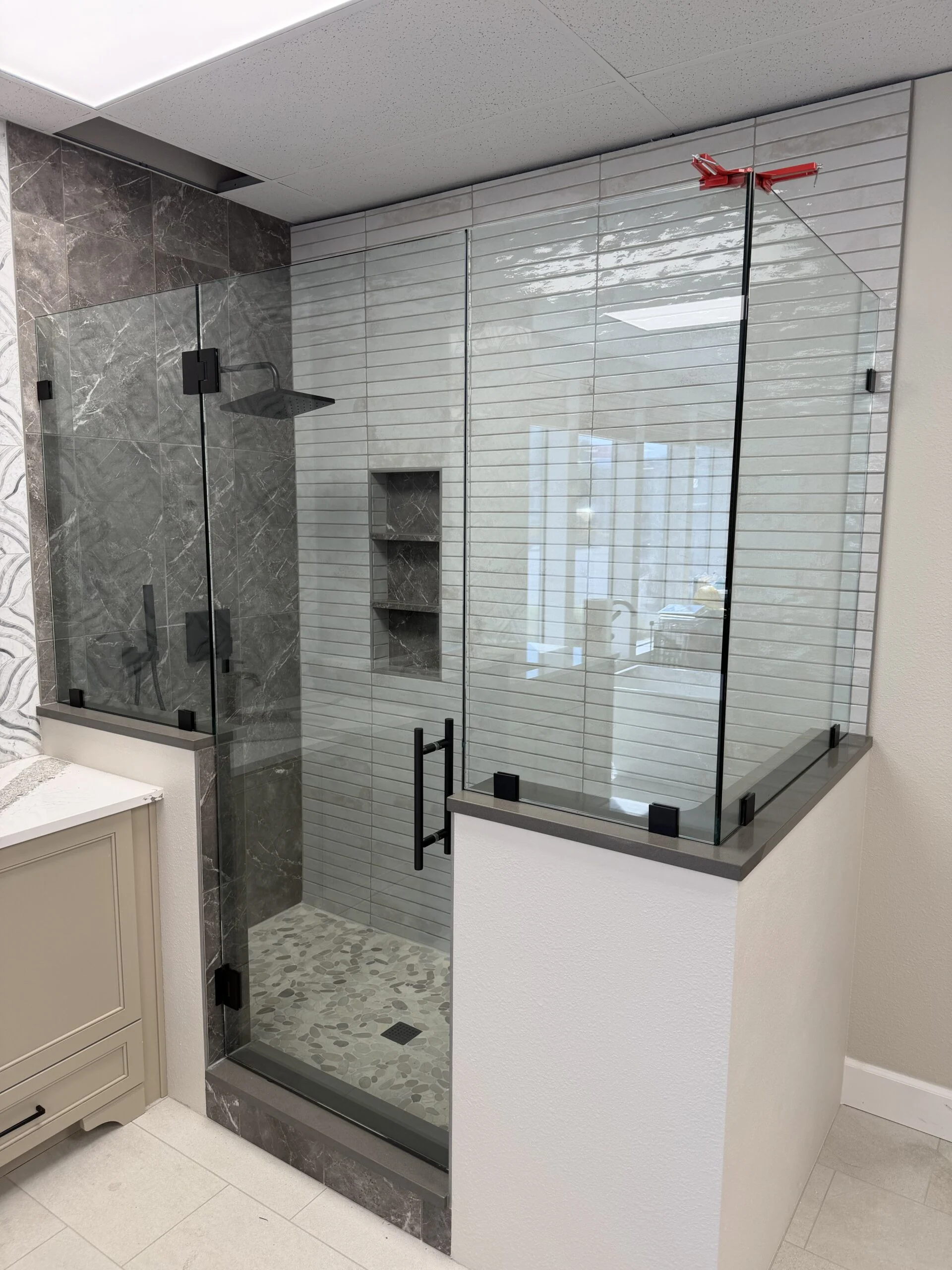 Frameless glass shower with matte black hardware on a knee wall
