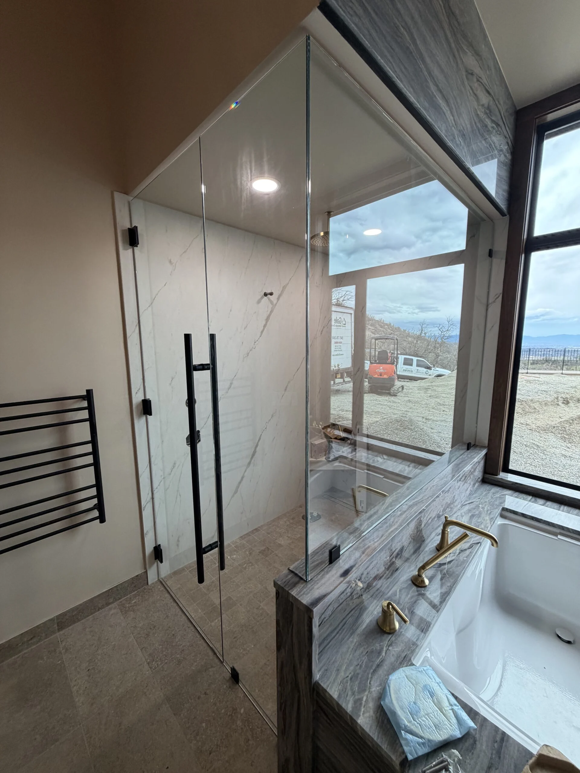 Frameless glass shower with a matte black ladder pull