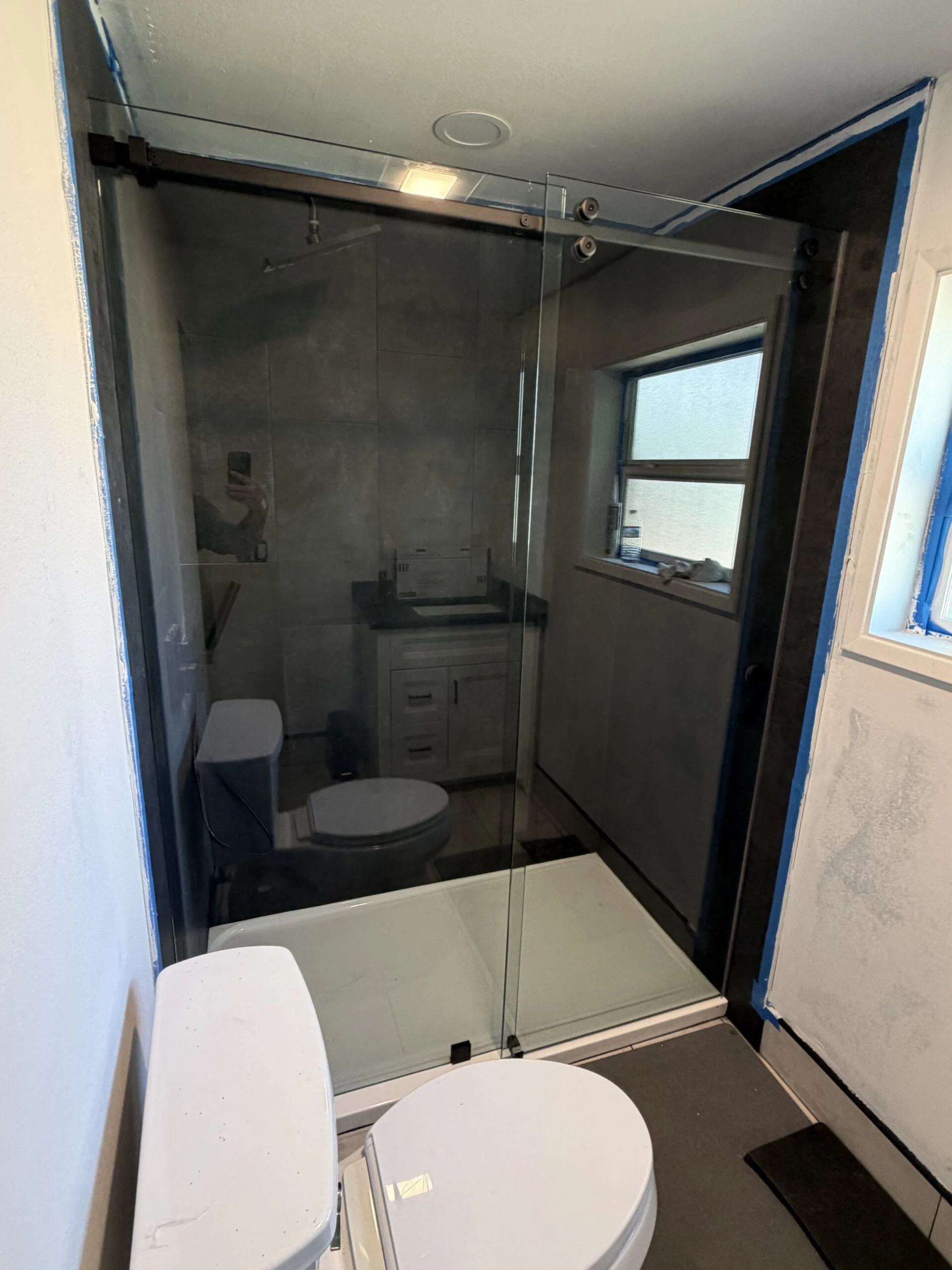 Frameless sliding shower door with black track in a bright bathroom