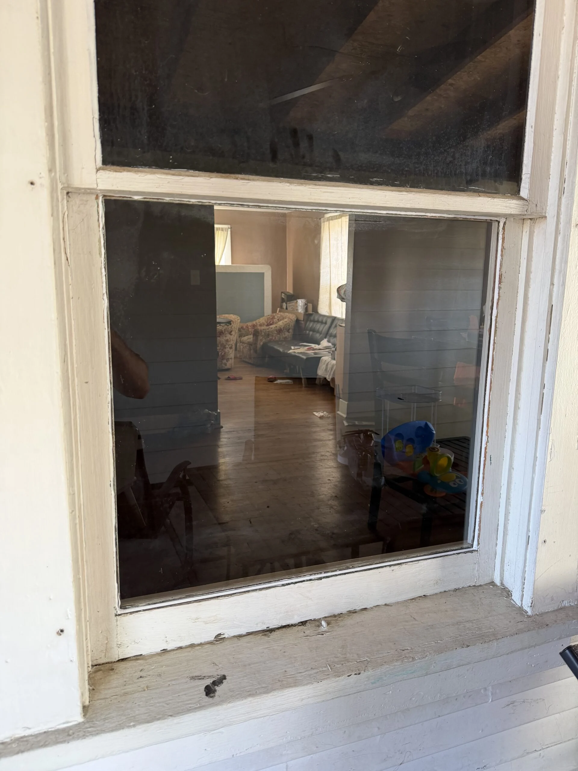 Old window with broken glass removed, looking into a room
