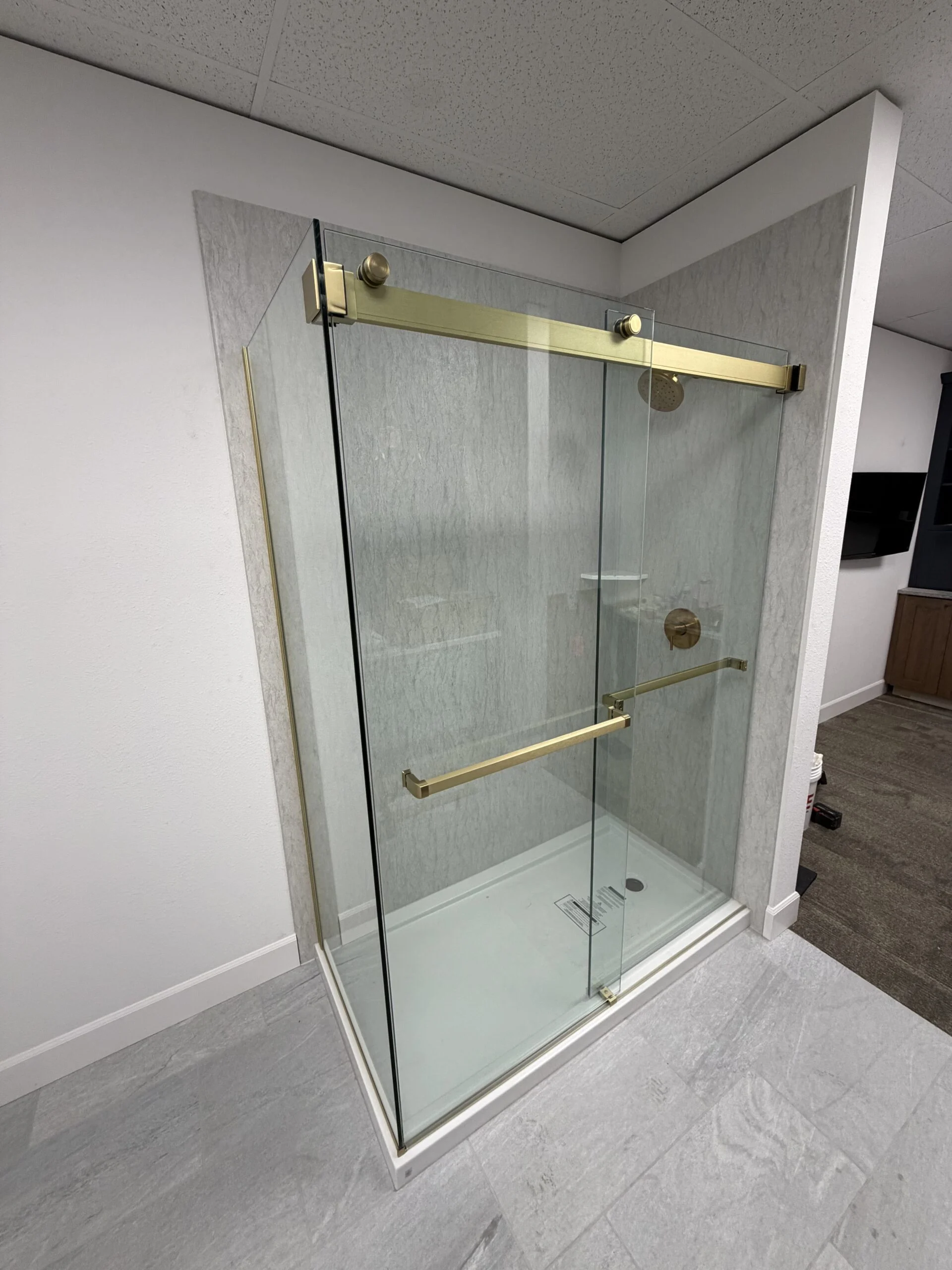 Sliding glass shower enclosure with brushed brass hardware
