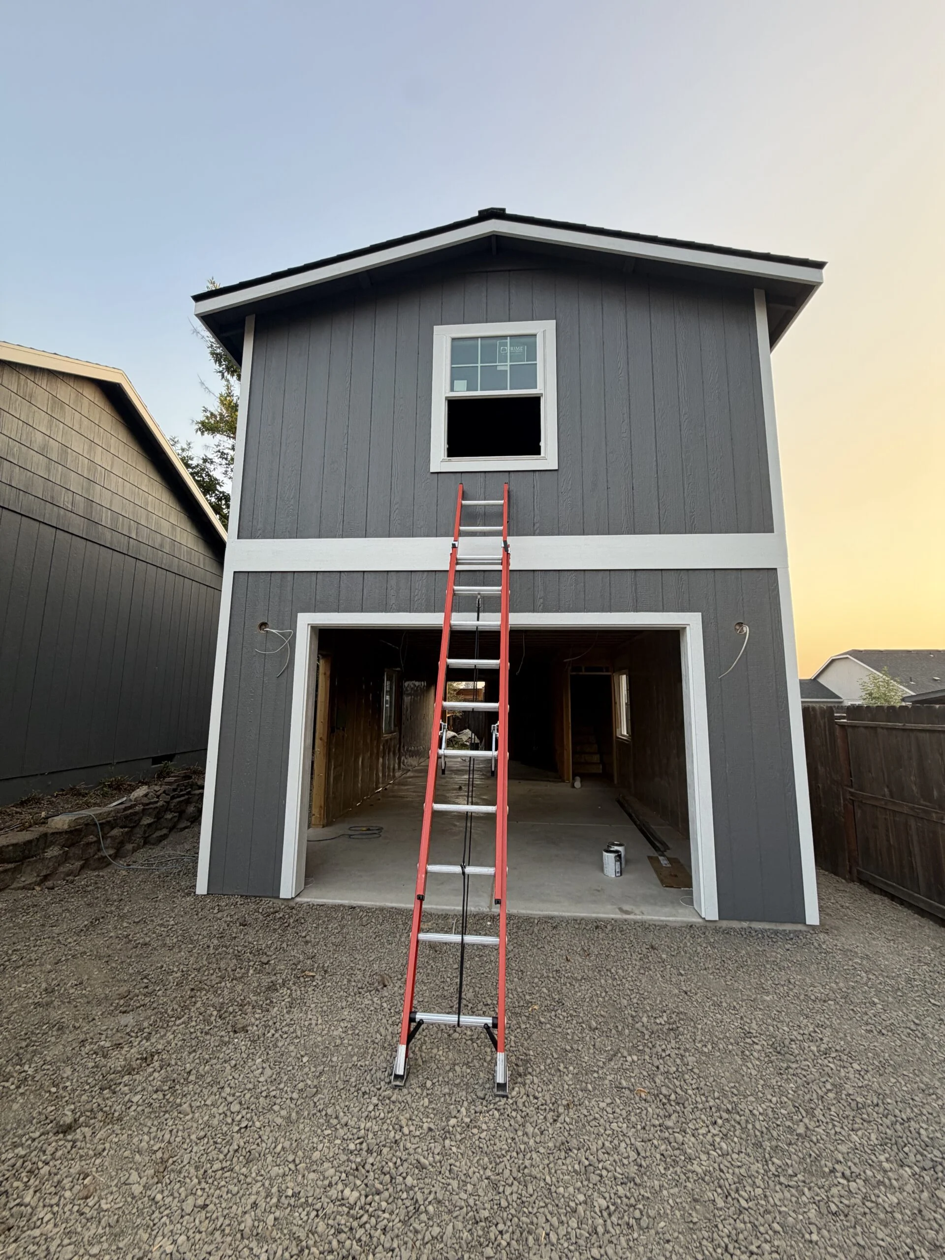 Two-story garage with a new upper window and ladder in front