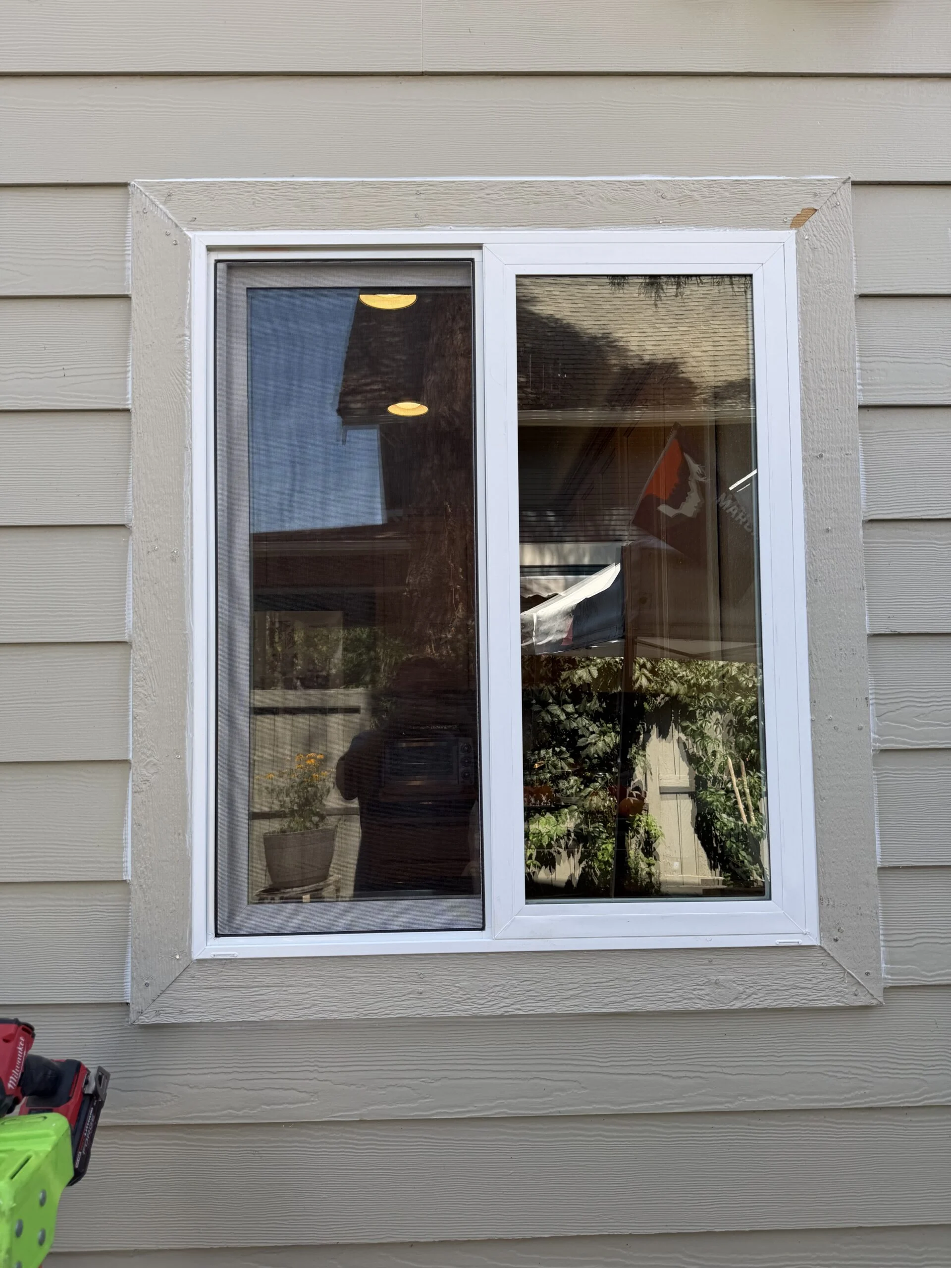 White sliding window set in tan lap siding